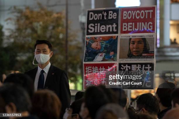 Protester holds a placard next to a plain clothes police officer as he protests against the Chinese government during a Liberal Democratic Party...