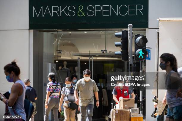 Pedestrians walk past the British multinational retailer Marks & Spencer store seen in Hong Kong.