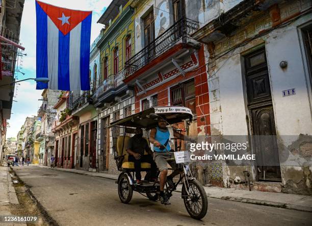 Bicitaxi drives along a street decorated with a huge Cuban flag in Havana, on October 27, 2021.