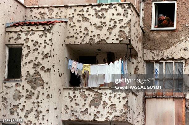 Resident tries to fix up a window of his flat in his bullet-riddled building in the eastern district of Mostar, southern Bosnia, on December 21 as a...