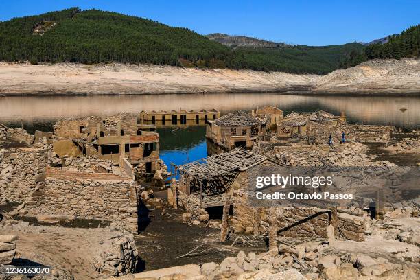 Tourists walk through the ruins of the partly submerged Aceredo village buildings as they emerge from the river Lima on October 27, 2021 in Lobios,...