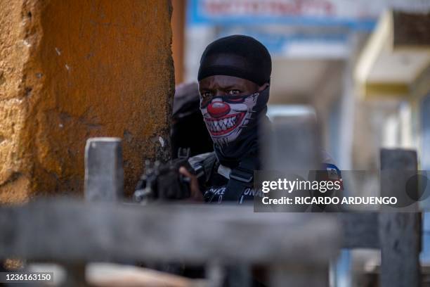 Haitian National Police officer points his rifle towards a barricade in the gang controlled area of Morne A Tuff during the third day of a general...