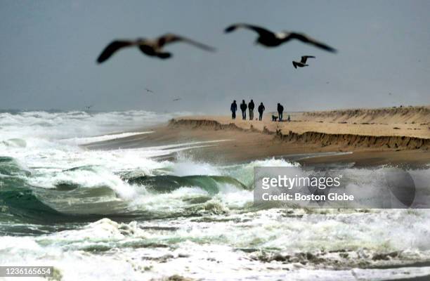 Orleans, MA People walk along Nauset Beach in Orleans, MA as heavy surf rolls in from an approaching Noreaster early Tuesday afternoon on October 26,...