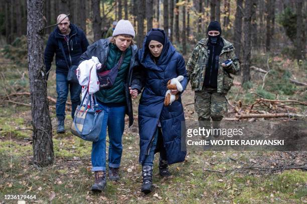Alaa Massini , refugee from Syria, speaks with Klara , an activist from the Grupa Granica , as they walk with border guard officers in the woods near...