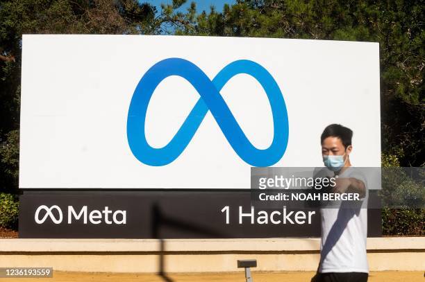 Person takes a selfie in front of a newly unveiled logo for "Meta", the new name for Facebook's parent company, outside Facebook headquarters in...