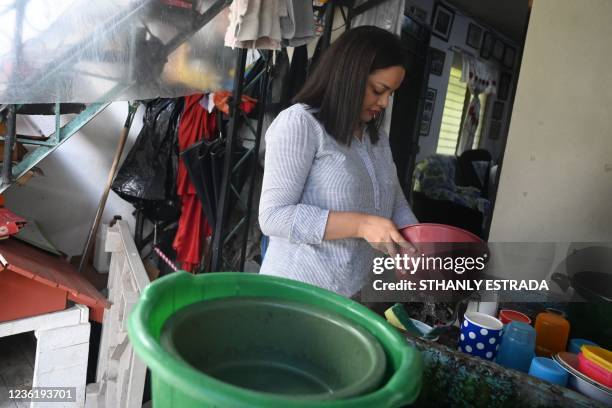 Cristina Navas washes dishes at her house in Soyapango, El Salvador on October 19, 2021. - Cristina, who lives in a populous neighborhood besieged by...