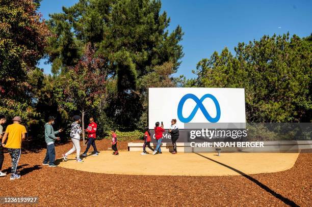 People visit a newly unveiled logo for "Meta", the new name for Facebook's parent company, outside Facebook headquarters in Menlo Park on October 28,...