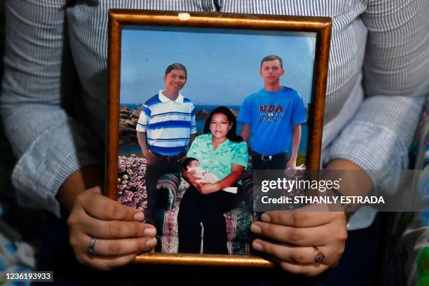 Cristina Navas poses holding a photo of her family at her house in Soyapango, El Salvador on October 19, 2021. - Cristina, who lives in a populous...