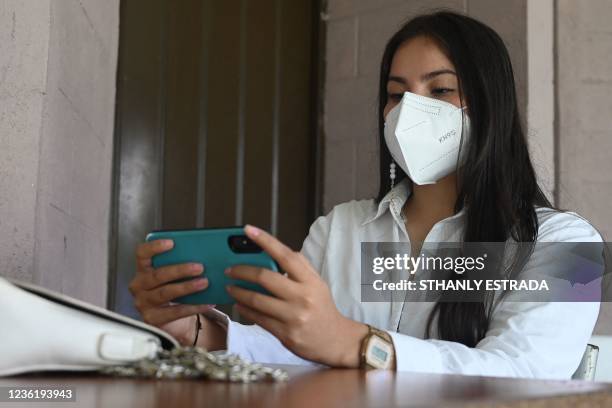 Marta Morales uses her cell phone during a virtual class in the Forever Foundation in Soyapango, El Salvador on October 19, 2021. - Marta, who lives...