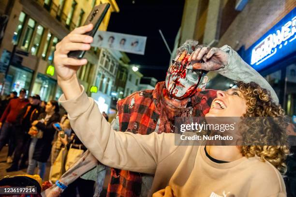 Woman is taking a selfie with one of the zombies, during the Zombie walk organized in the center of Arnhem, on October 28th, 2021.