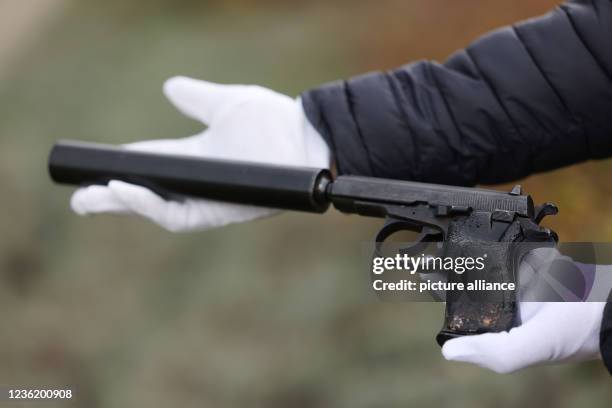 October 2021, North Rhine-Westphalia, Meckenheim: An employee of the Federal Criminal Police Office holds one of the murder weapons, a Ceska 83, 7.65...