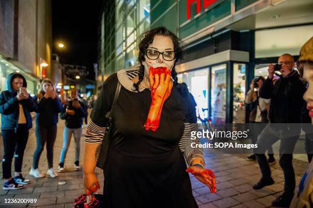 Female zombie walks with a fake human arm in her mouth. Last two years the zombie walk was canceled due to the Coronavirus pandemic, however this...