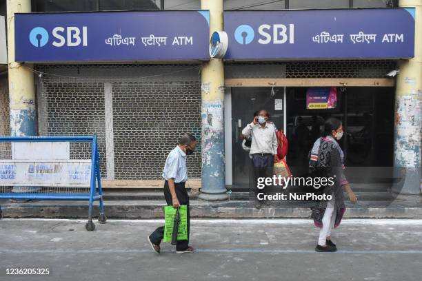 People exit an State bank of India ATM counter at a street in Kolkata , India , on 29 October 2021 . SBI profits jumped 67% in Q2 2021 to Rs 345...