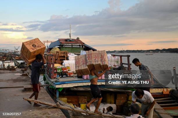 Labours load the food boxes onto a boat at Yangon Jetty on October 29, 2021.
