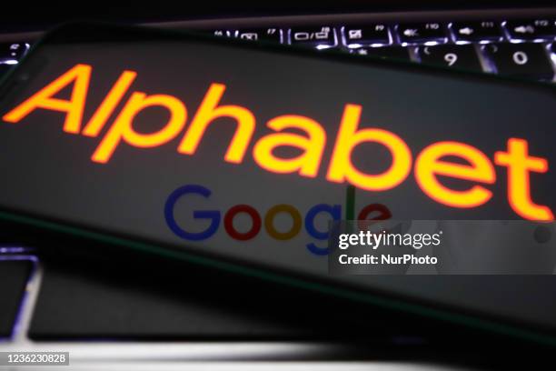 Alphabet logo displayed on a phone screen and Google logo reflected on this device are seen in this illustration photo taken in Krakow, Poland on...