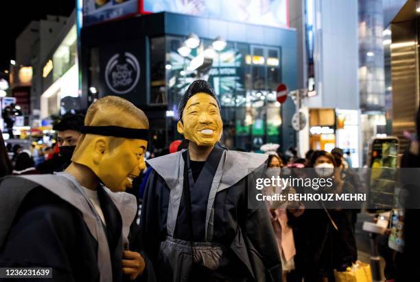 People wearing masks of Japanese comedians Tetsuro Degawa and Miyazon pose during a Halloween parade at Shibuya district in Tokyo on October 30, 2021.