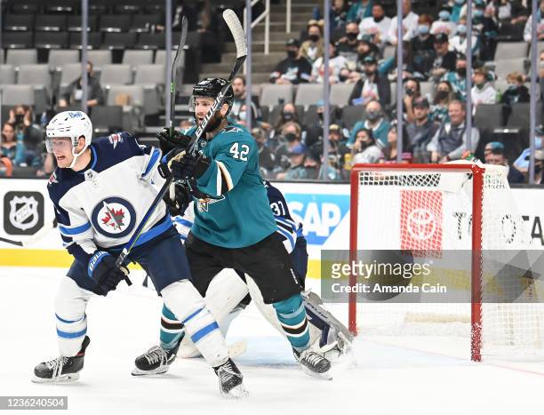 Jonah Gadjovich of the San Jose Sharks battles for position in front of the net against Andrew Copp of the Winnipeg Jets in a regular season game at...