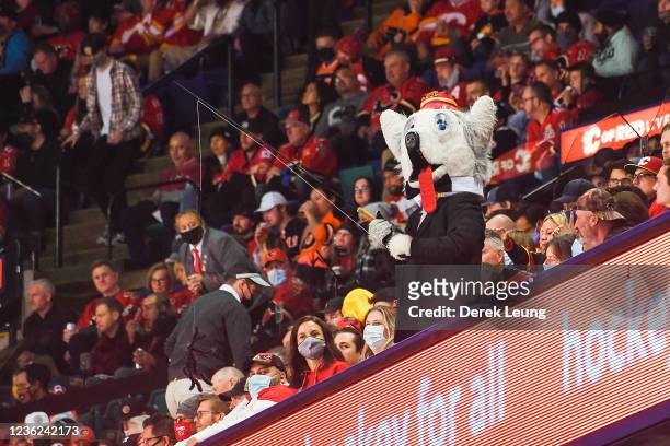 The Calgary Flames' mascot Harvey the Hound uses a fishing rod and fake spider to scare fans in the lower bowl during a break in play against the...