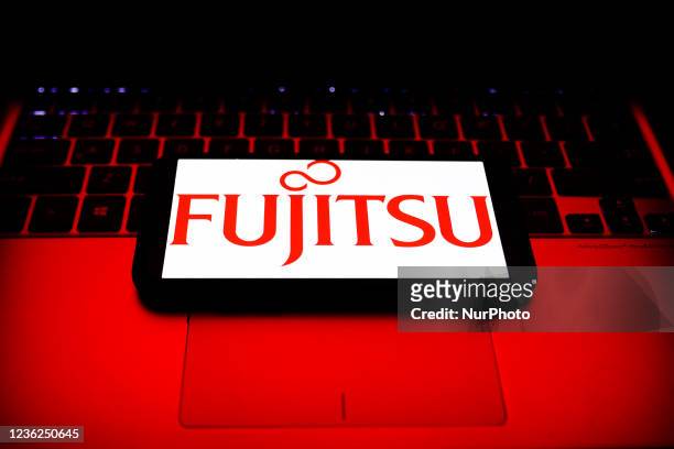 Fujitsu logo displayed on a phone screen and a laptop keyboard are seen in this illustration photo taken in Krakow, Poland on October 30, 2021.