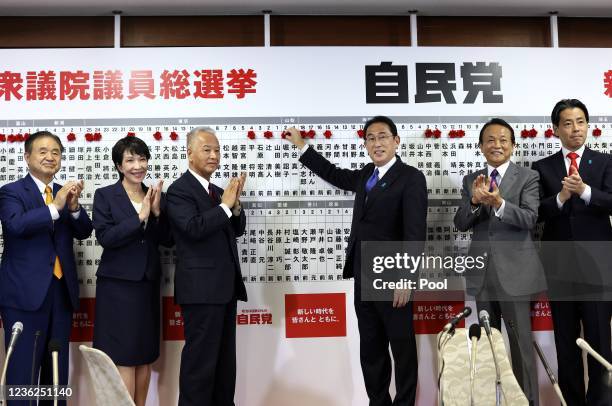 Japan's Prime Minister and ruling Liberal Democratic Party leader Fumio Kishida poses with key party members as he puts rosettes by successful...