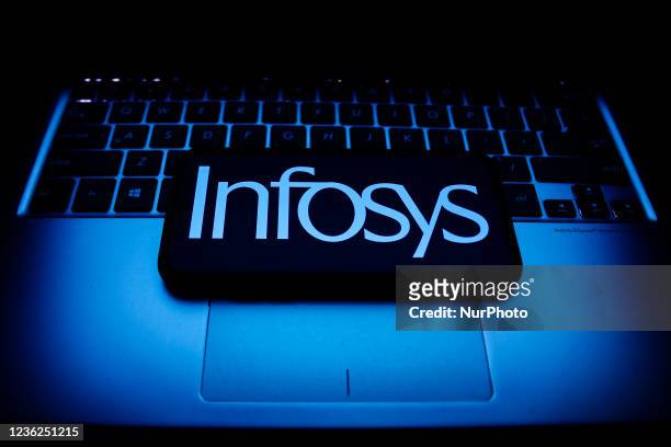 Infosys logo displayed on a phone screen and a laptop keyboard are seen in this illustration photo taken in Krakow, Poland on October 30, 2021.