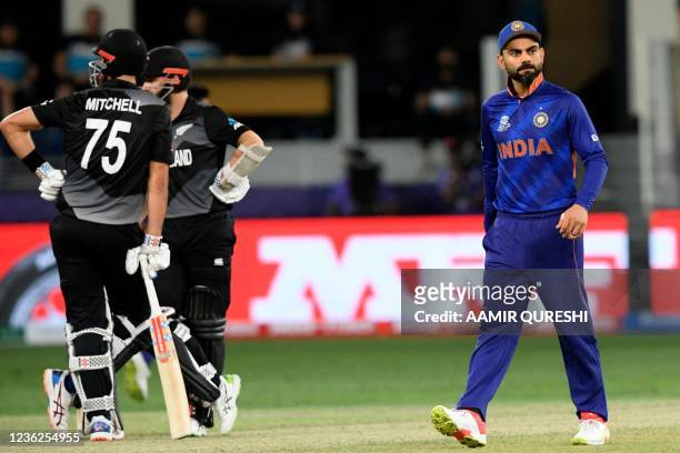 India's captain Virat Kohli walks past New Zealand's captain Kane Williamson and Daryl Mitchell during the ICC mens Twenty20 World Cup cricket match...