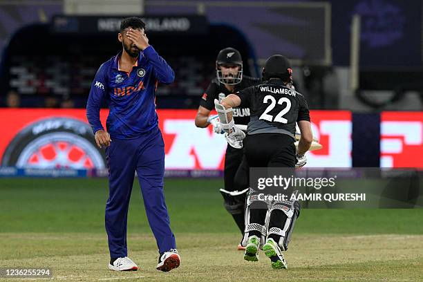 India's Varun Chakravarthy reacts as New Zealand's captain Kane Williamson and Daryl Mitchell run between the wickets during the ICC mens Twenty20...