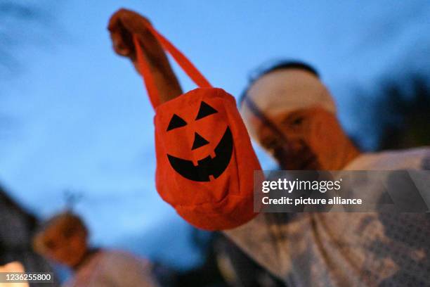 October 2021, Lower Saxony, Göttingen: Costumed children with bags of candy parade through town on Halloween night. Halloween is the celebration of...