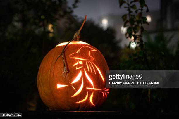 This photograph shows a jack-o'-lantern made with a carved pumpkin representing a witch and her broom, during Halloween night, in Lausanne, on...
