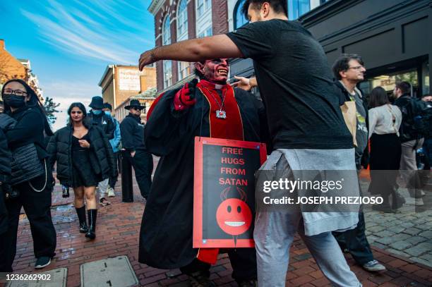 Dan Lavoie, dressed as Satan, gives a hug to a stranger on Halloween in Salem, Massachusetts on October 31, 2021. - The city is the location of the...