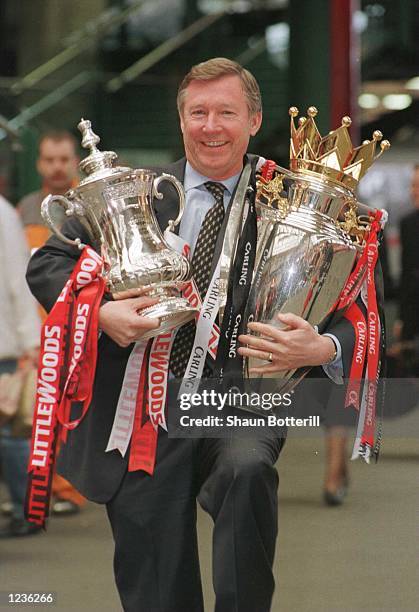 12th May 1996; Manchester United manager Alex Ferguson with the FA Cup and Premiership trophy on his arrival at Manchester's Victoria station....