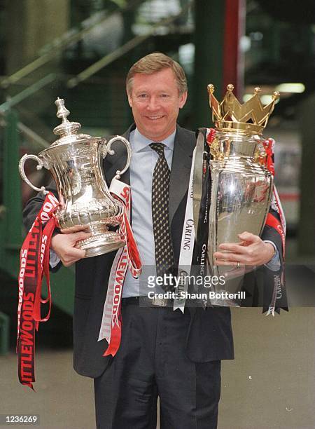 12th May 1996; Manchester United manager Alex Ferguson with the FA Cup and Premiership trophy on his arrival at Manchester's Victoria station....
