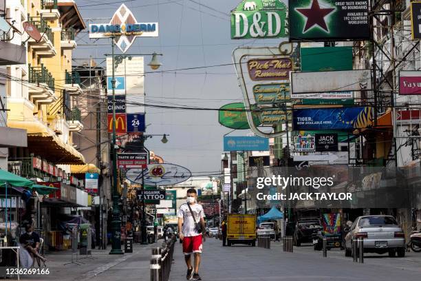 Man walks along Khao San Road -- a once popular tourist strip -- in Bangkok on November 1 as Thailand allows travellers vaccinated against the...