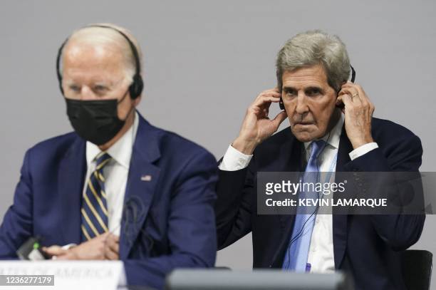 Climate Adviser John Kerry adjusts his headphones next to U.S. President Joe Biden as they attend a meeting focused on action and solidarity at the...
