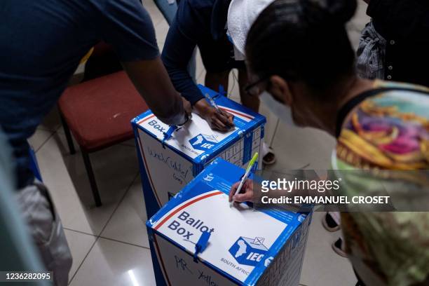 Party delegates sign the ballot boxes after supervising an electoral commission official sealing them at the Fordsburg Primary school polling station...