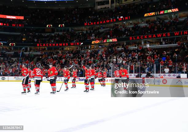 Blackhawks gather at center ice and raise their sticks to the fans after winning their first game during a game between the Chicago Blackhawks and...