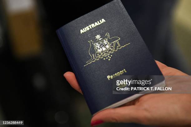 Traveler displays an Australian passport for a photograph as they check-in for a flight to Sydney, Australia on Qantas Airways Ltd. Inside the Tom...