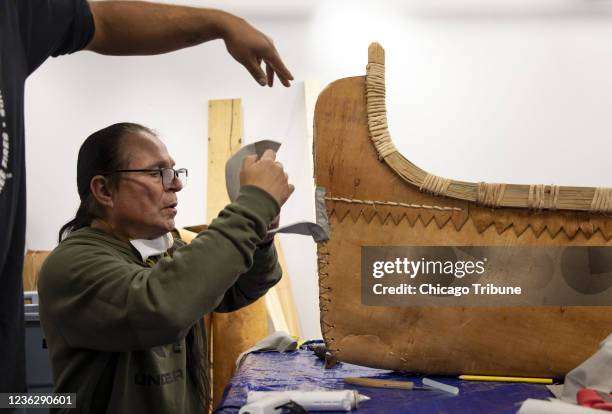 Wayne Valliere attaches a piece of canvas to the end of the traditional Ojibwe canoe he is constructing Monday, Oct. 25, 2021 inside an academic...