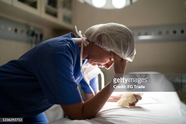 besorgte ärztin im gesundheitswesen im operationssaal im krankenhaus - emotional stress stock-fotos und bilder