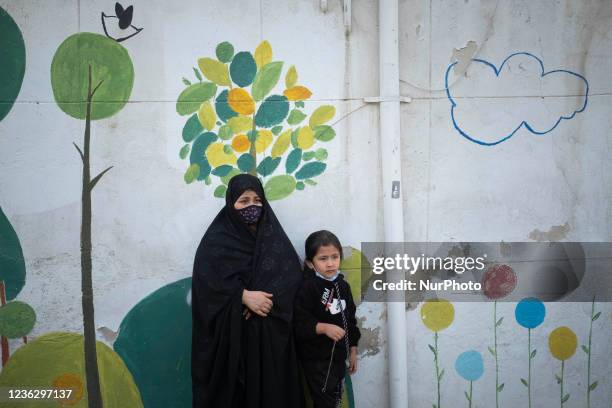 An Afghan refugee woman and her young daughter stand out of the Farhang school in the first day of the new academic year in southern Tehran on...