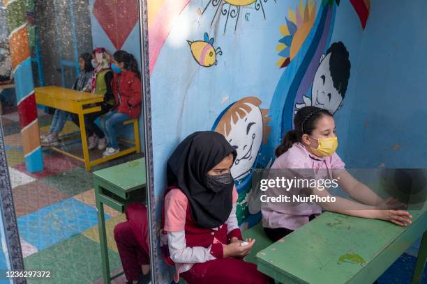 Afghan refugee schoolgirls sit on benches at the Farhang school in the first day of the new academic year in southern Tehran on November 1, 2021....