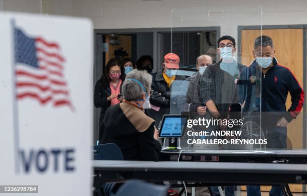 Voters wait for their ballots at a school cafeteria being used as a polling location on election day in McLean, Virginia on November 2, 2021. - With...