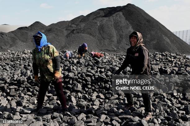 Workers sort coal near a coal mine in Datong, China's northern Shanxi province on November 3, 2021.