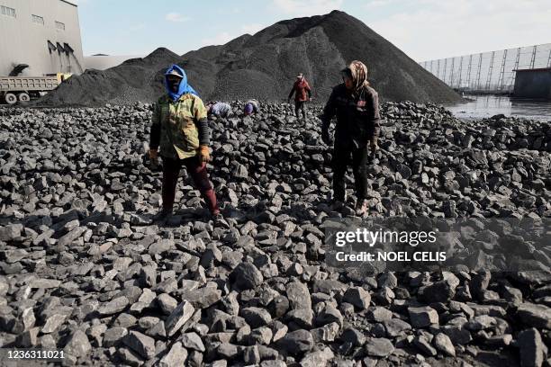 Workers sort coal near a coal mine in Datong, China's northern Shanxi province on November 3, 2021.