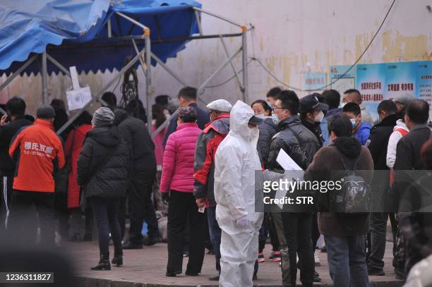 Medical worker looks on as residents line up to undergo Covid-19 coronavirus tests in Harbin, in China's northern Heilongjiang province on November...