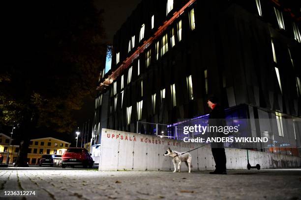 Man holds a dog on the leash at night as he stands in front of the concert hall "Uppsala Konsert & Kongress" in Uppsala, Sweden, on November 2, 2021....