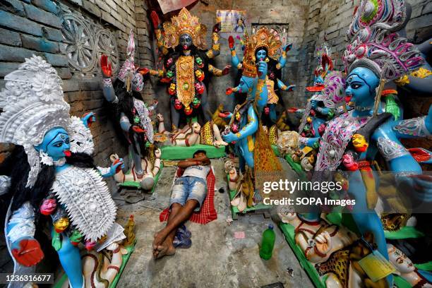 An artist takes a nap in his studio surrounded by idols, during the Kali Puja festival in Kumartuli. Goddess Kali is being worshipped as a savior...