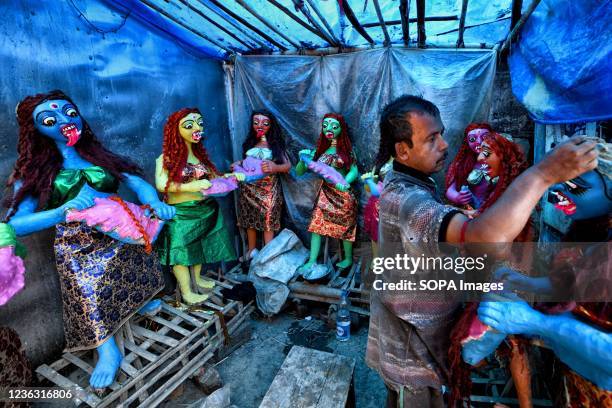 An artist seen making final touches to idols of a Goddess Kali, during the Kali Puja festival in Kumartuli. Goddess Kali is being worshipped as a...