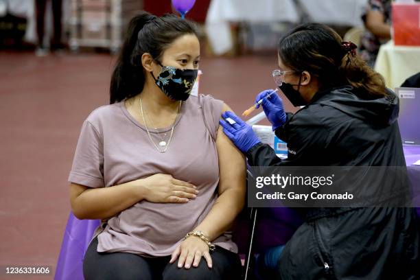 Nicole Fahey, of Altadena, six months pregnant, receives a Pfizer vaccination booster shot from RN Veronique Vida at Eugene A. Obregon Park on...