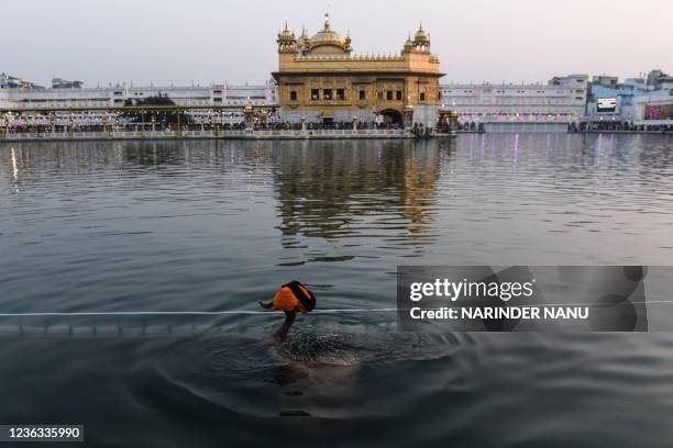 Sikh devotee takes a holy dip in the sarovar on the occasion of "Bandi Chhor Divas" at the illuminated Golden Temple, in Amritsar on November 4, 2021.